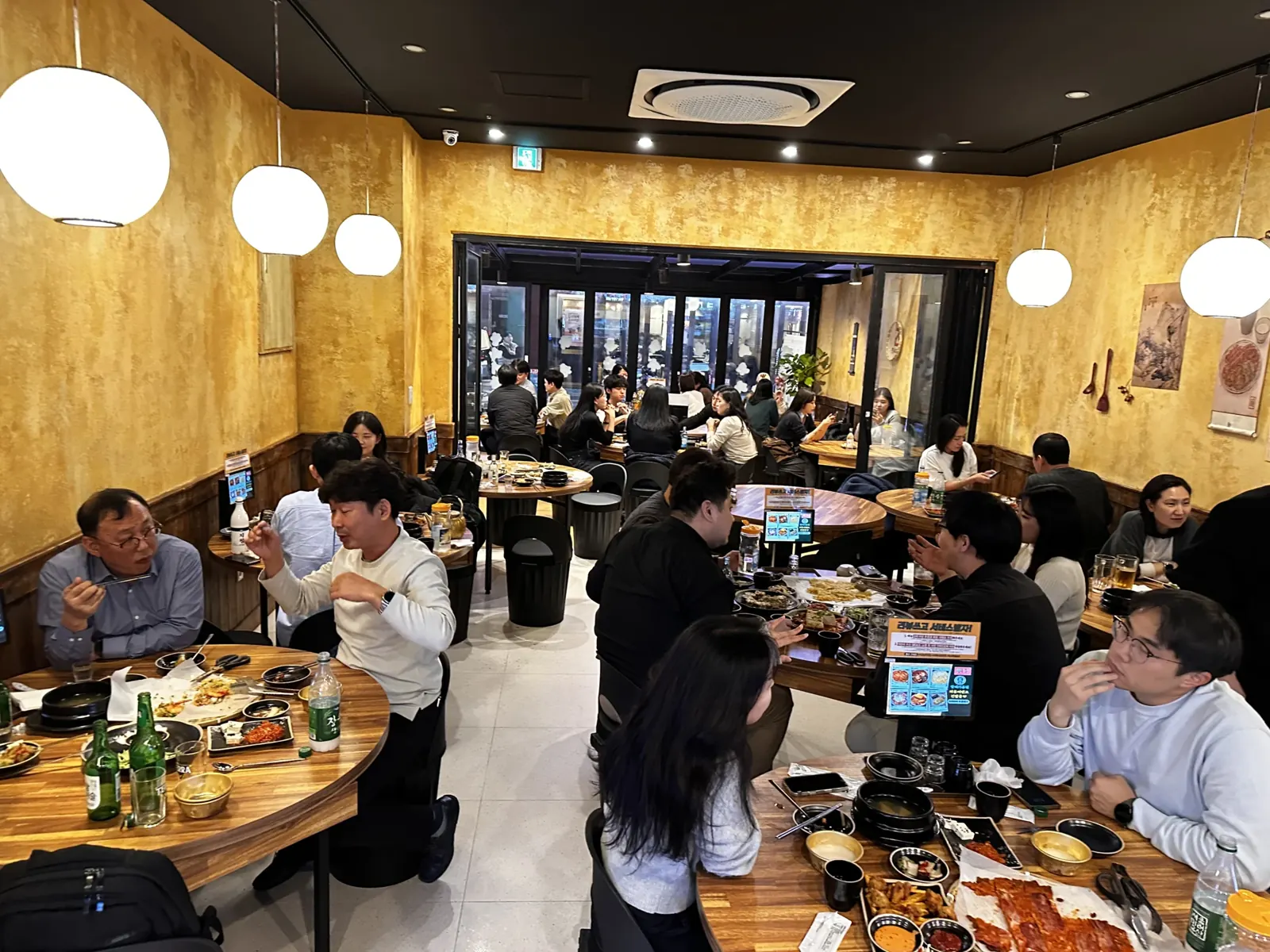 손님이 가득한 매장 홀 노란 벽 인테리어